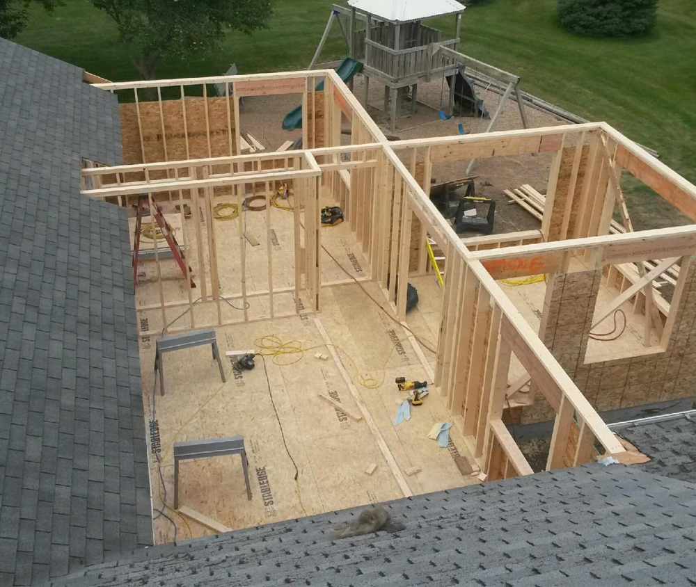 A room addition framed and sheathed, tied into the existing roofline.
